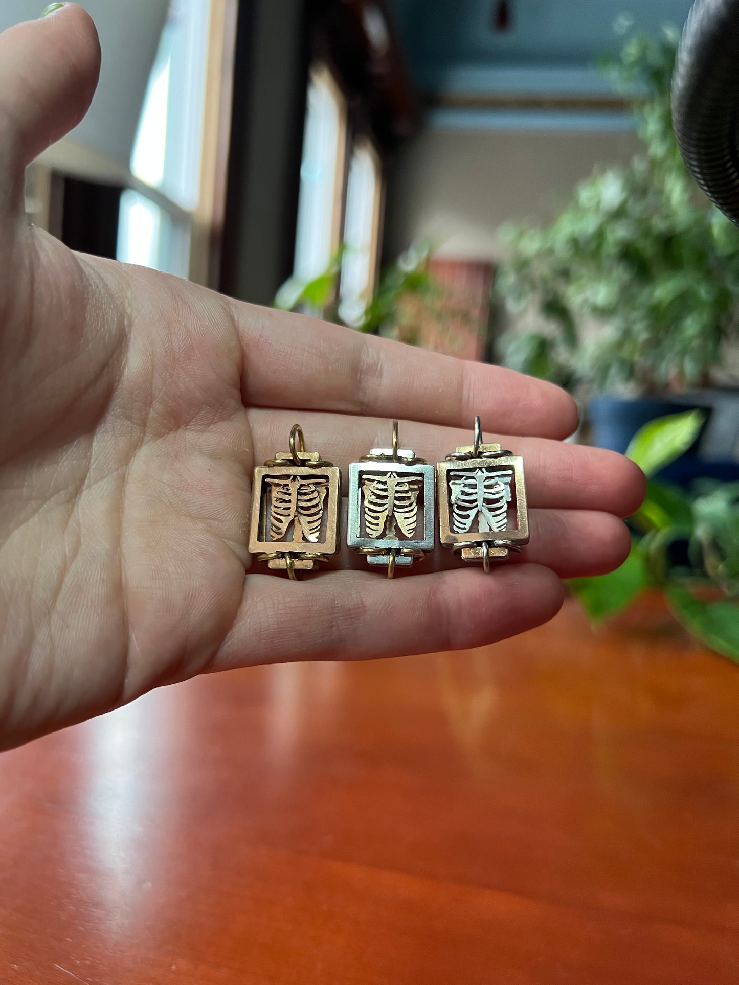 From left to right there are three pendants. Left most is bronze front frame, with bronze Ribcage, and bronze wire. Middle is silver front frame, with bronze Ribcage, and bronze wire. Right most is bronze front frame, with silver Ribcage, and silver wire